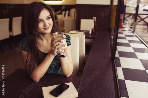 Brunette woman sitting at the cafe reading book  studing and drinking coffee and waiting someone who is late. Copy Space