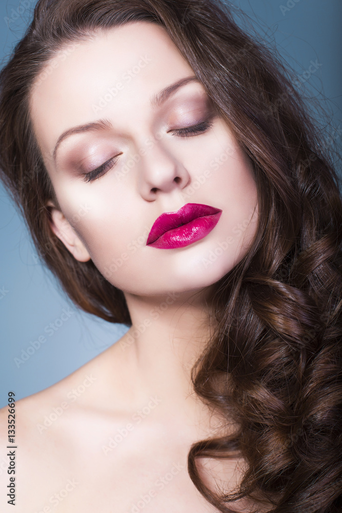 Beautiful brunette woman with creative make up violet eye shadows full red lips, blue eyes and curly hair with her hand on her face Beautiful brunette woman with creative make up violet eye shadows full red lips, blue eyes and curly hair with her hand on her face