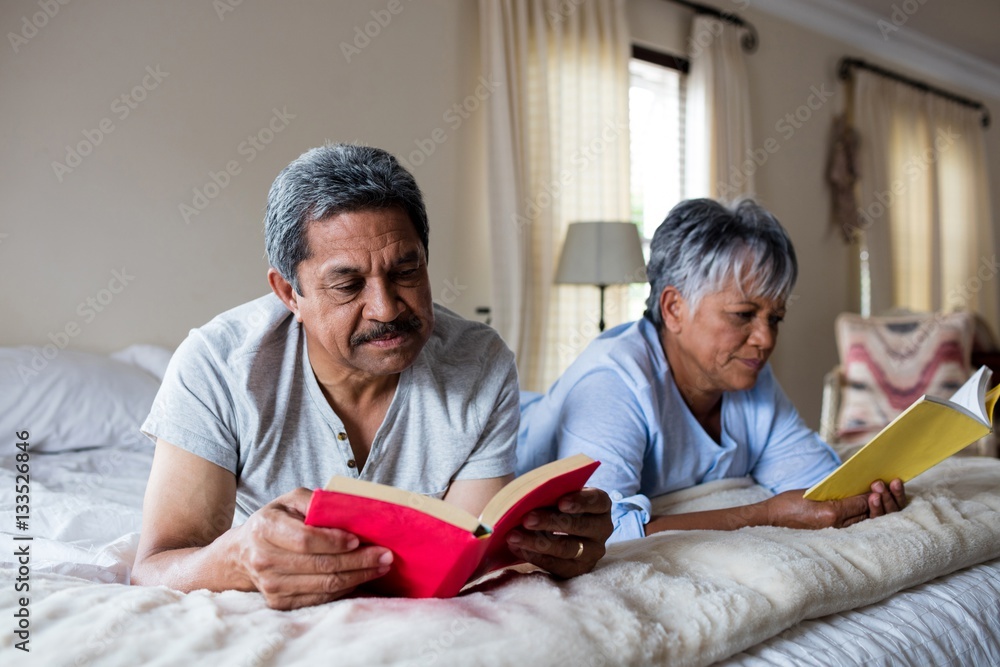 Senior couple reading books on bed Senior couple reading books on bed