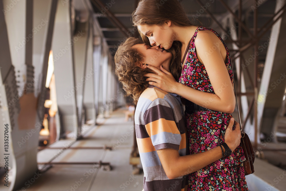 Young couple hugging in the summer daylight on a bridge construc