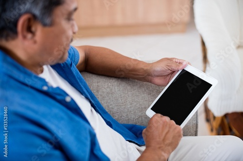 Senior man using digital tablet in living room