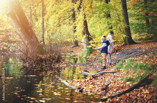 Two little children looking at autumn pond