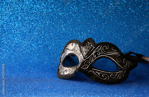 elegant venetian mask on blue glitter background.