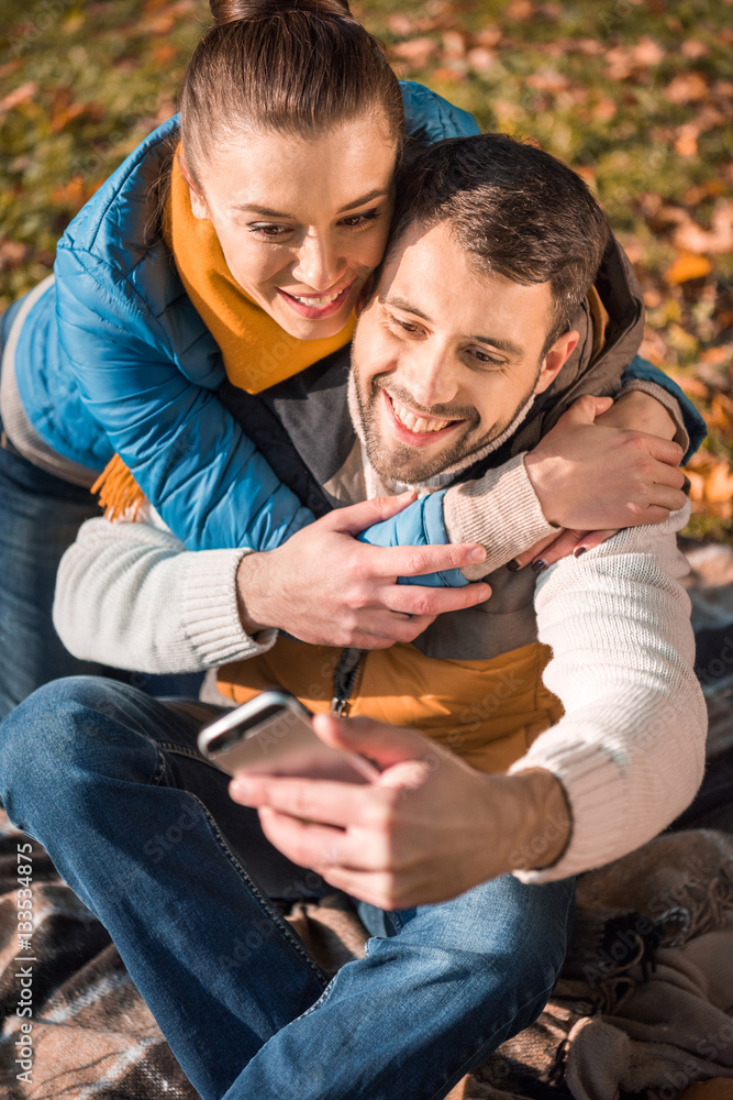 Fototapeta premium Beautiful smiling couple looking at smartphone