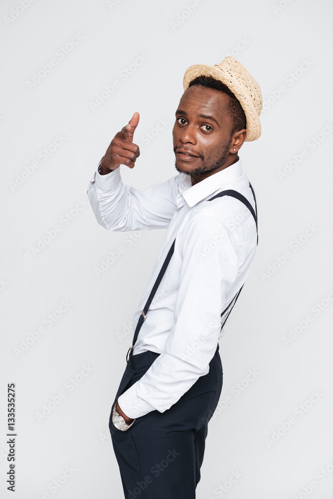 Handsome african man wearing hat posing in studio and pointing. Handsome african man wearing hat posing in studio and pointing.