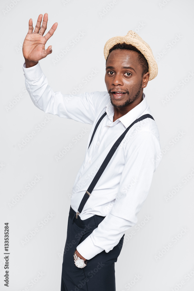 Handsome african man wearing hat posing in studio and waving Handsome african man wearing hat posing in studio and waving