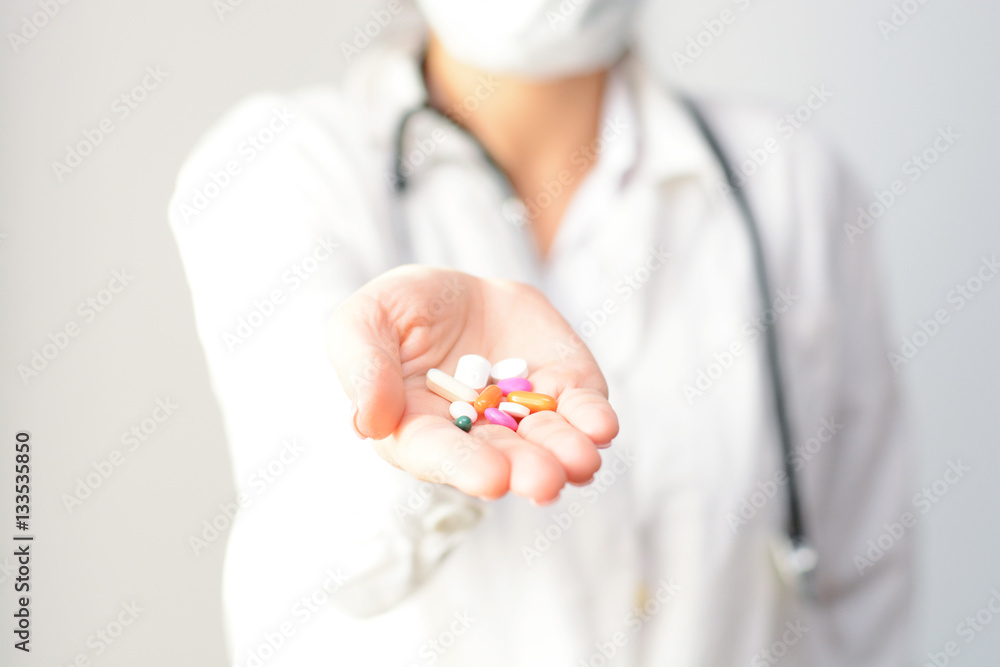 Female doctor displaying a handful of tablets and pills in her palm Female doctor displaying a handful of tablets and pills in her palm
