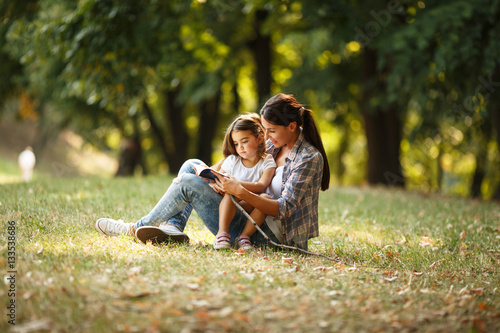 Fotografie Mother and daughter relaxing in park