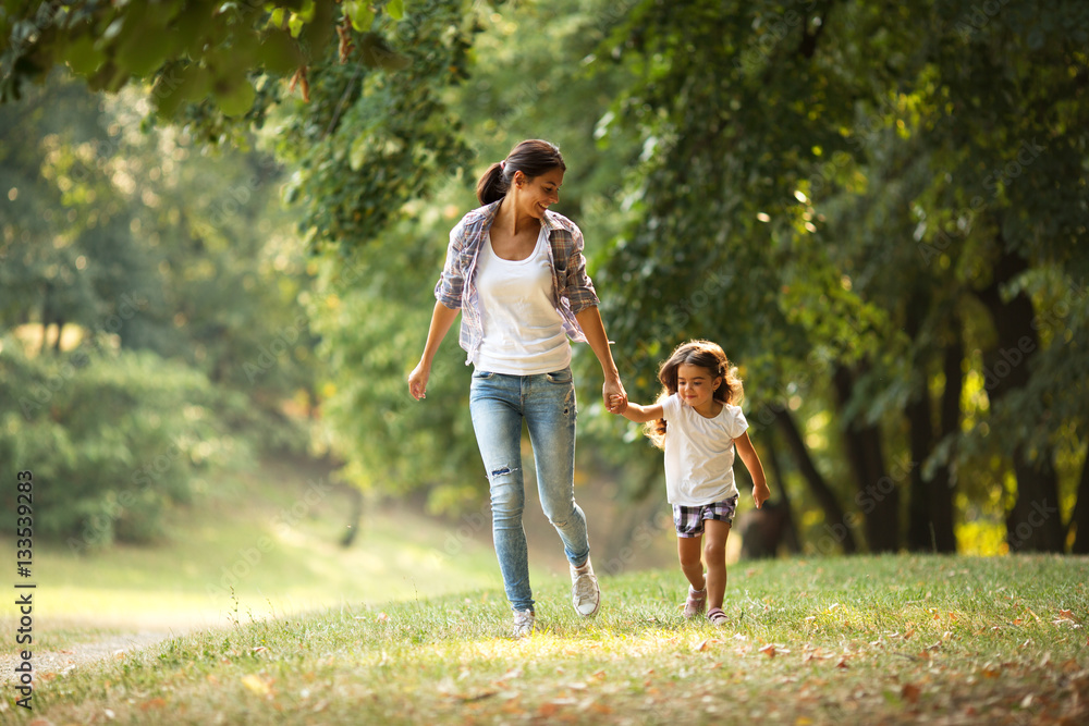 Mother and daughter playing and running around the park on beautiful morning. Mother and daughter playing and running around the park on beautiful morning.