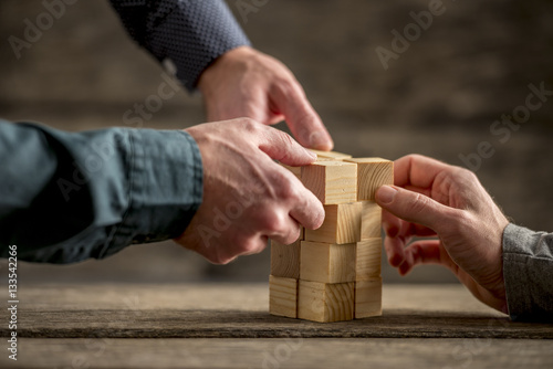 Hands building a tower of wood blocks photo