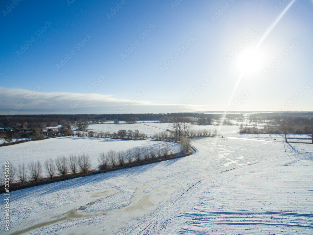 aerial view of beautiful snowy landscape with sun and blue sky in germany aerial view of beautiful snowy landscape with sun and blue sky in germany