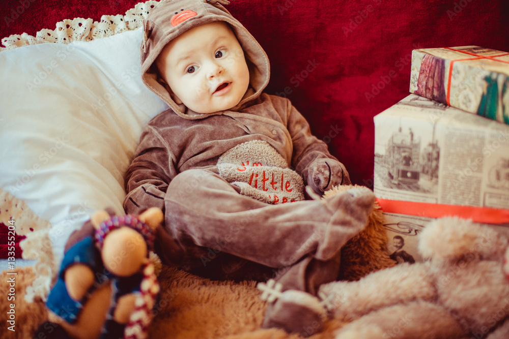 The small baby sits near presents The small baby sits near presents
