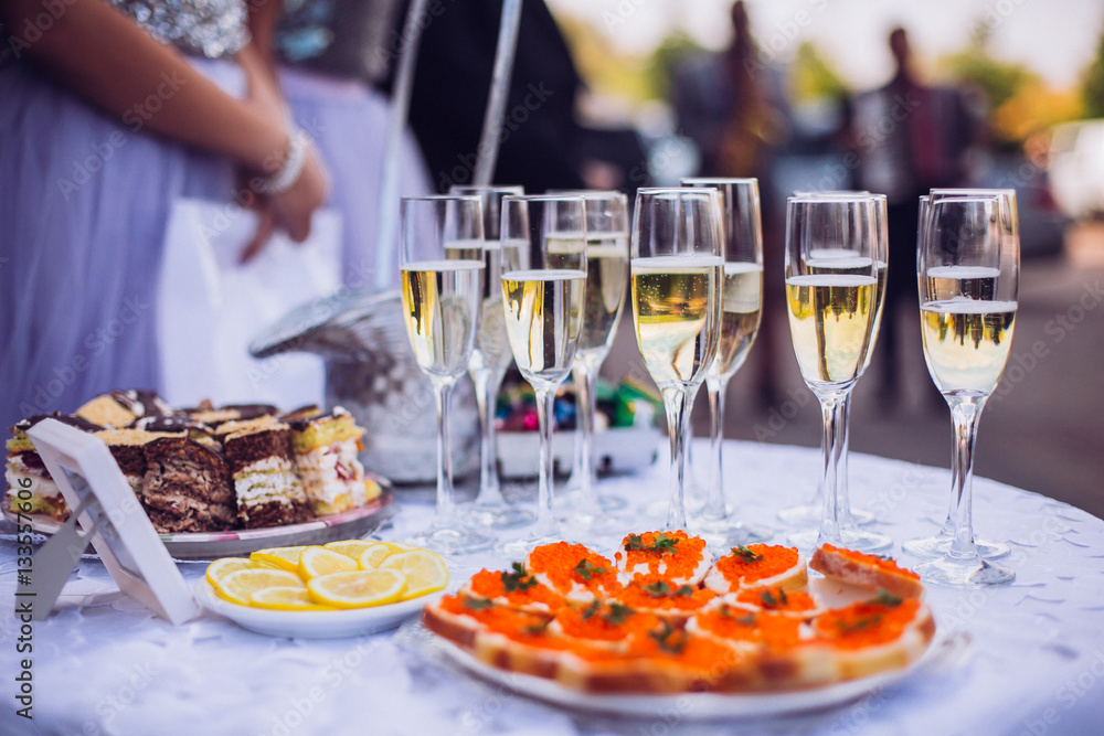 Glasses of champagne on table served for buffet catering party outdoors, close up