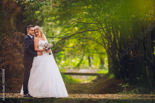 Obraz na płótnie Bride and groom in a park kissing.couple newlyweds bride and groom at a wedding in nature green forest are kissing photo portrait.Wedding Couple w salonie