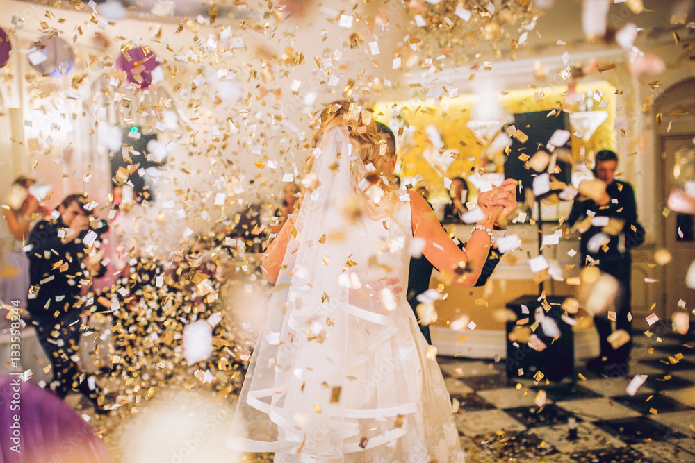 beautiful caucasian couple just married and dancing their first dance confetti around