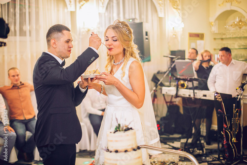 Bride and groom cut the wedding cake and feed each other. Wedding sweet cake. photo