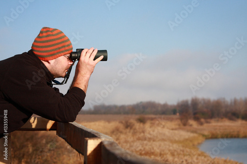 A young man watching birds in the wetland early morning