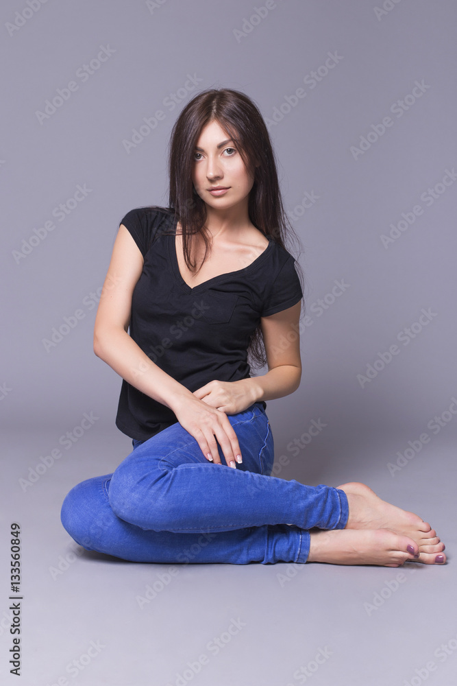 Portrait of a beautiful brunette woman model posing in jeans and