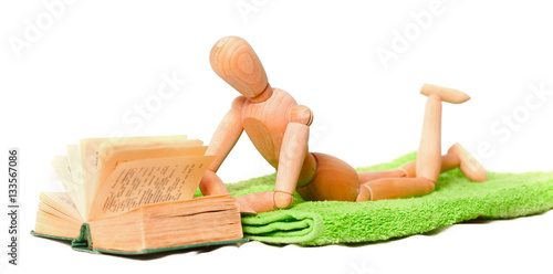 wooden mannequin on lies on a towel and reads the book photo