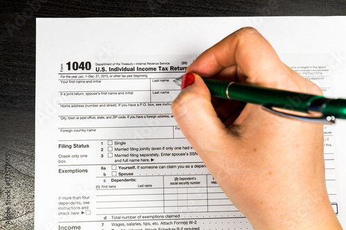 Woman filling US tax form. Tax form US business income office hand fill concept. Selective focus.