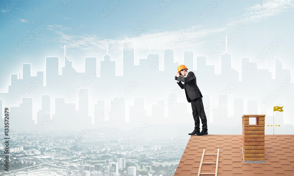 Engineer man standing on roof and looking in binoculars. Mixed media Engineer man standing on roof and looking in binoculars. Mixed media