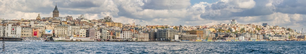 Panorama of Cityscape of Golden horn with ancient and modern buildings in Istanbul Turkey from the Bosphorus strait on a sunny day with background cloudy sky