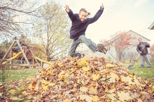 фотографія Boy taking a break from chores to jump in the leaves