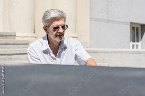 Fashionable senior man sitting on stairs photo