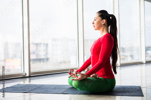 Guptasana. Beautiful yoga woman practice in a big window hall background. Yoga concept. photo