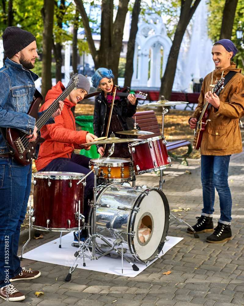Festival music band. Friends playing on percussion instruments in city park. Fountain and trees in the background. Festival music band. Friends playing on percussion instruments in city park. Fountain and trees in the background.