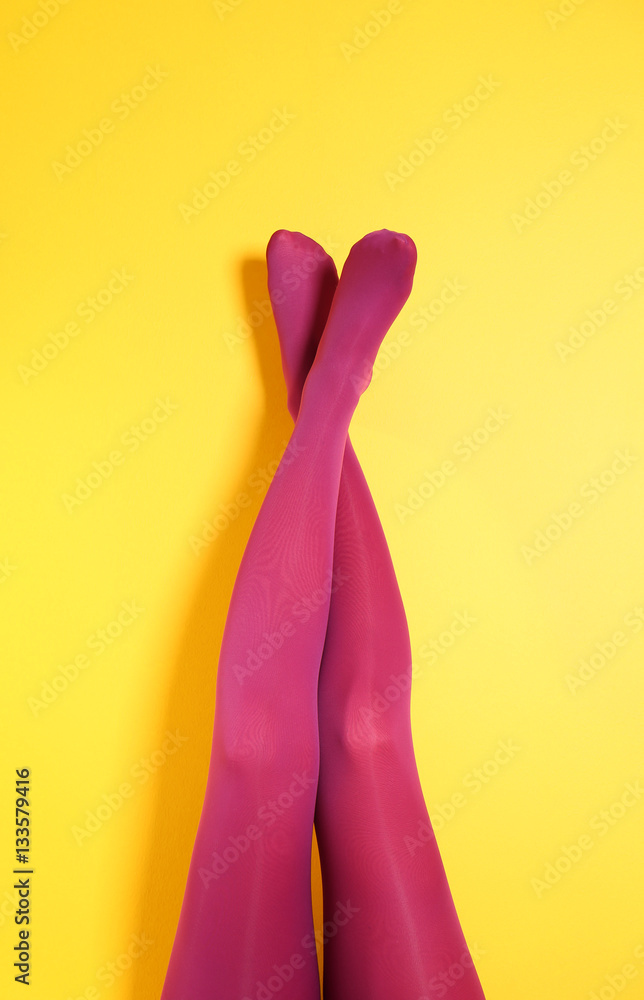 Beautiful woman legs in color tights on yellow background Beautiful woman legs in color tights on yellow background