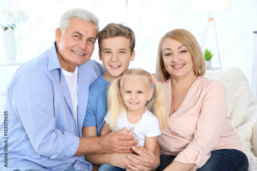 Cute children with grandparents sitting on sofa in living room Cute children with grandparents sitting on sofa in living room