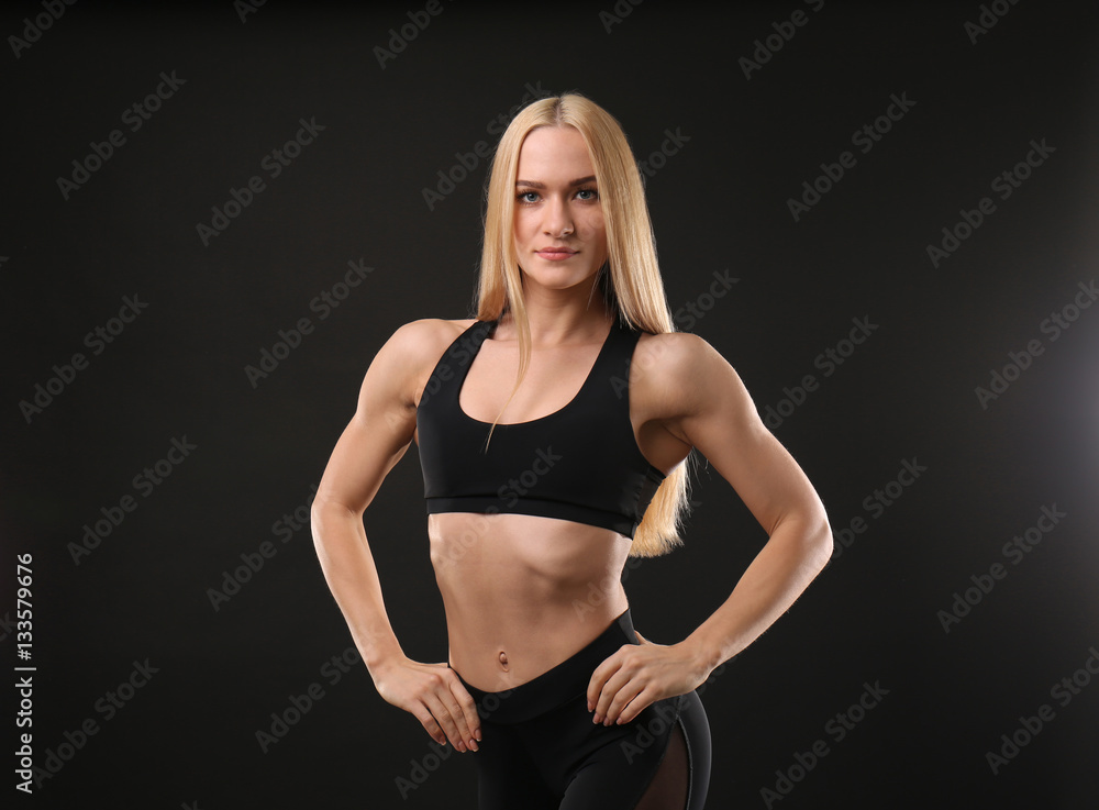 Fototapeta premium Young athletic woman on black background