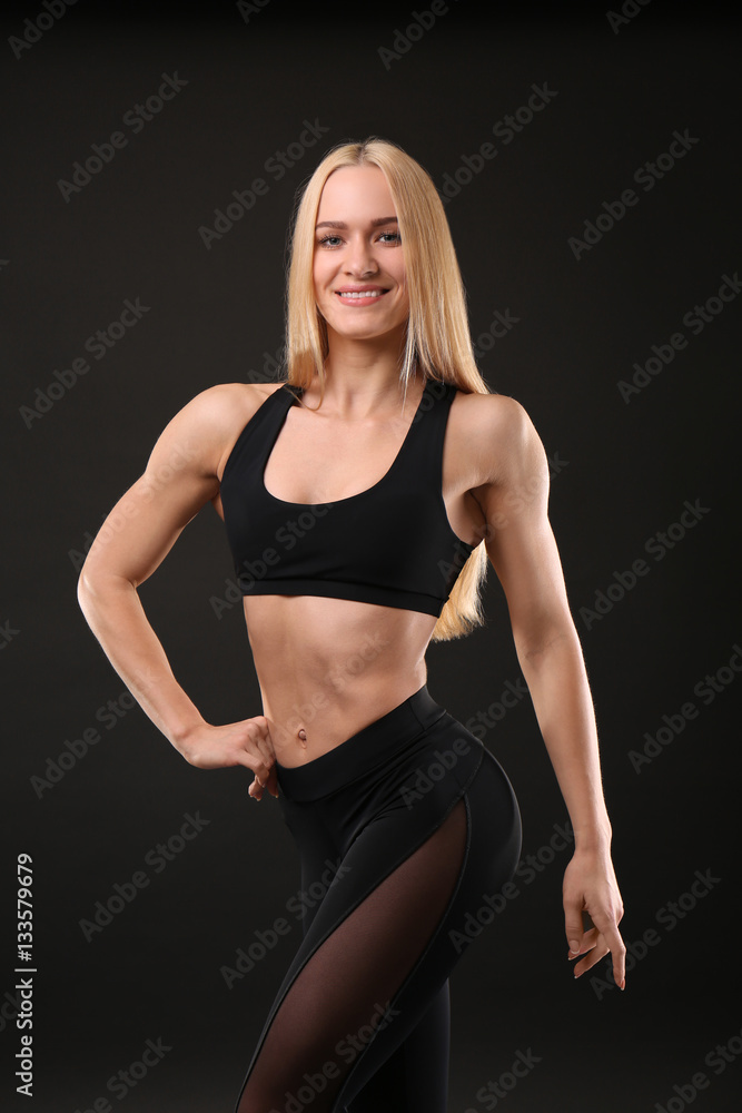 Young athletic woman on black background