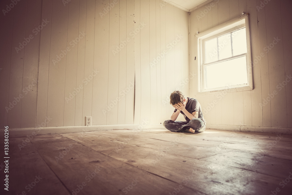 Sad boy alone in a bare room Sad boy alone in a bare room