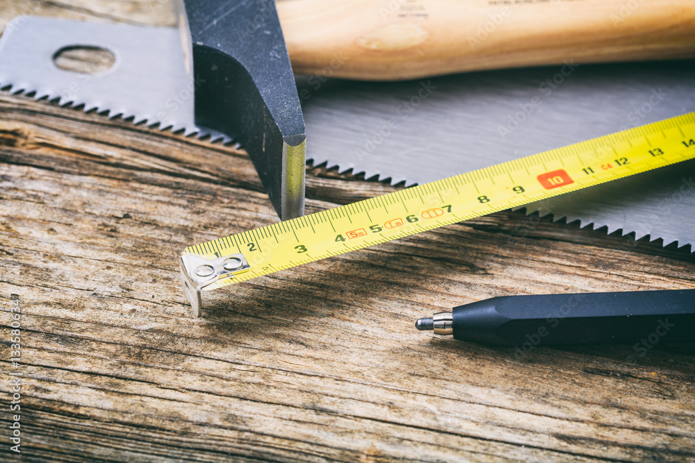 Hammer and hand saw on wooden background