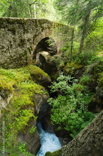 Ancient Roman stone bridge over a river gorge deep in a French forest