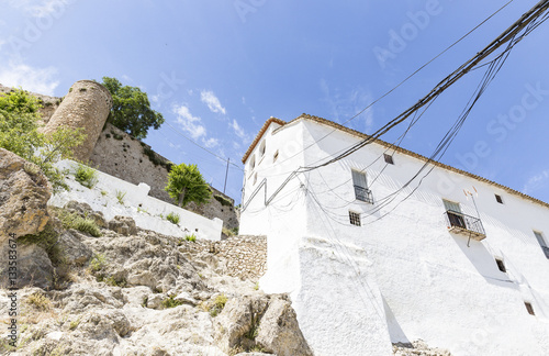 a white building with electric cables and the ancient castle of Moclin  Granada  Spain