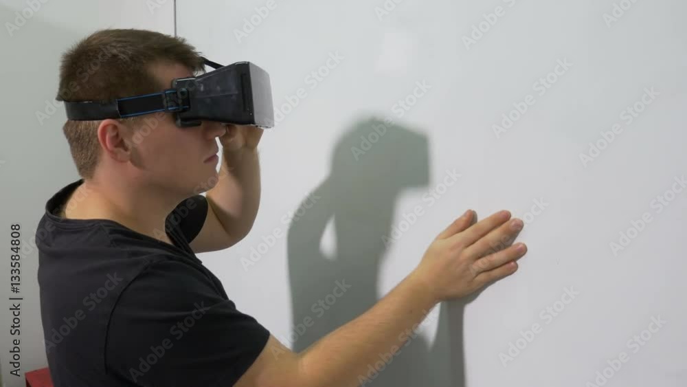 Man using ultimate VR 3d gadget touching an interactive whiteboard Man using ultimate VR 3d gadget touching an interactive whiteboard
