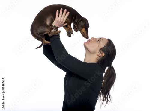 Caucasian brunette holds her dachshund dog in air giving it a kiss