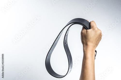 Vászonkép Hand holding leather belt for punishment, family violence  conce