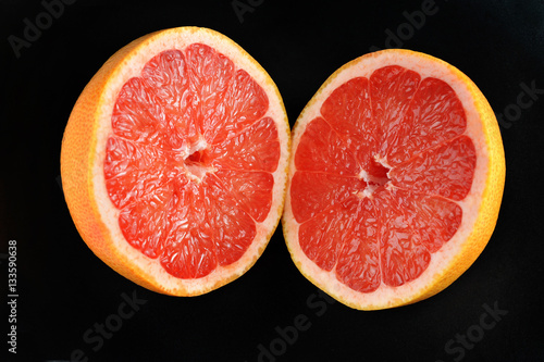 two halves of cut grapefruit lying on black