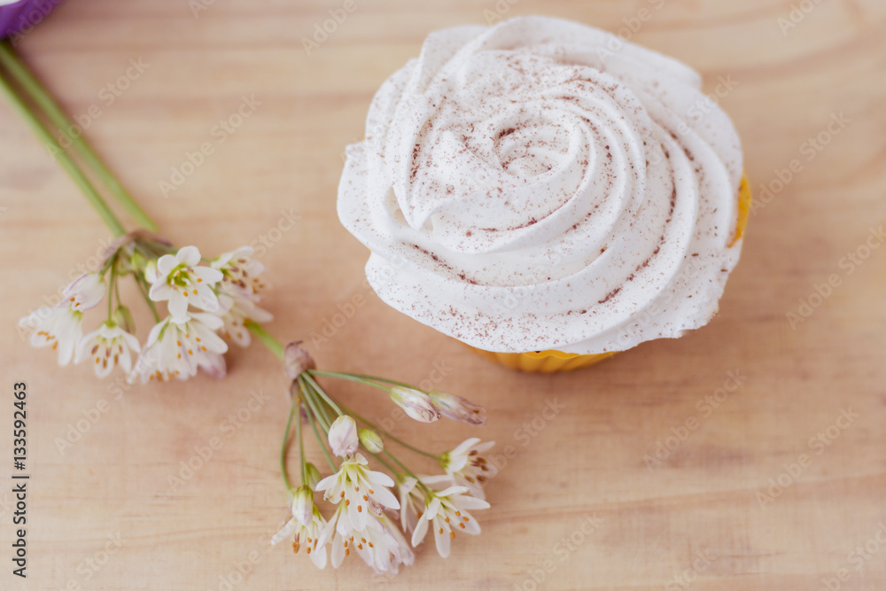 Vanilla cupcake with white frosting and flowers on a table Vanilla cupcake with white frosting and flowers on a table