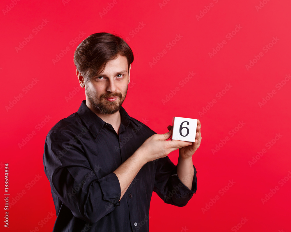 Man holding a cube with the number six. Numerals. A man shows a cube with the number six Man holding a cube with the number six. Numerals. A man shows a cube with the number six