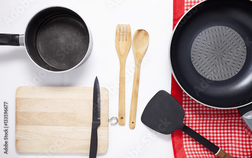 Black frying pan with cooking utensils on white background.