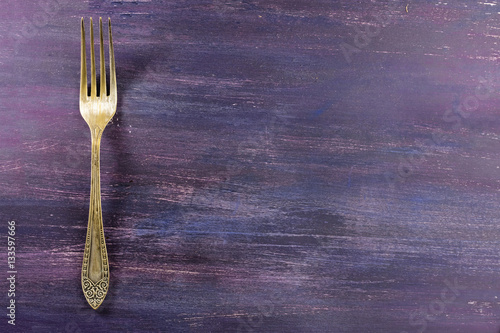 Vintage fork on purple background with copyspace