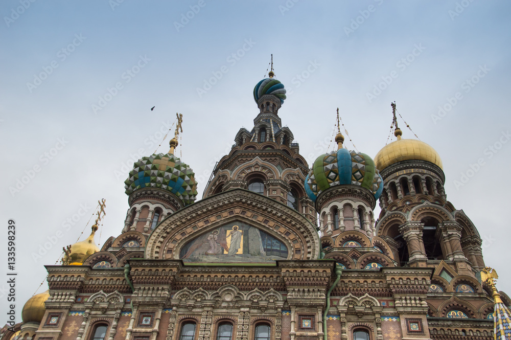 Ornate Exterior of Our Savior on Spilled Blood Russian Orthodox Church with colorful and handsomely decorated onion domes with crosses on top. Photographed from below.
