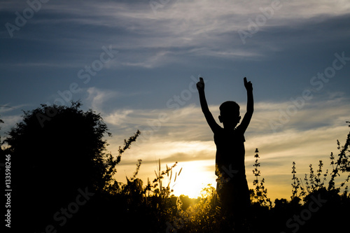 Children standing lift hand bye sun silhouette.