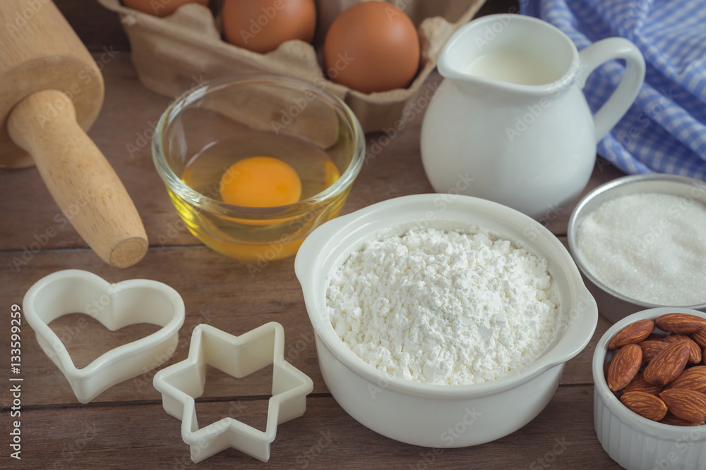 Baking ingredients flour, egg, milk, almonds, sugar on table Baking ingredients flour, egg, milk, almonds, sugar on table