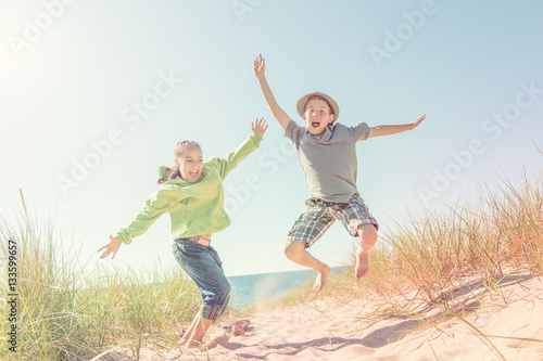 Boy and girl jumping in the dunes at the beach